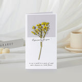 Greeting card with yellow flowers and text on a white surface