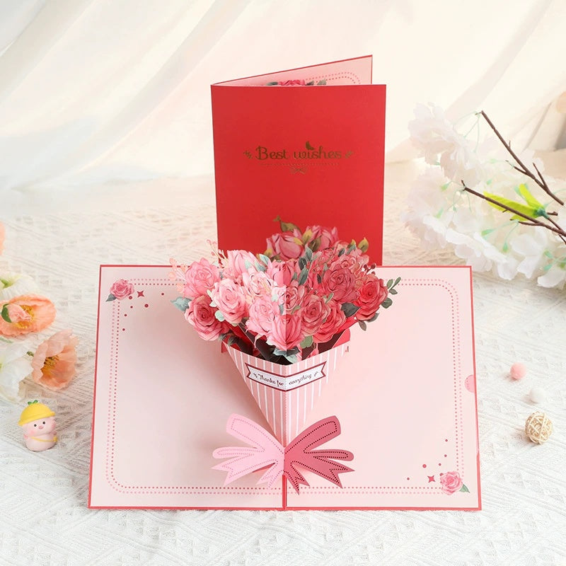 Greeting card with a 3D bouquet of pink flowers and a red envelope labeled 'Best wishes' on a light background.
