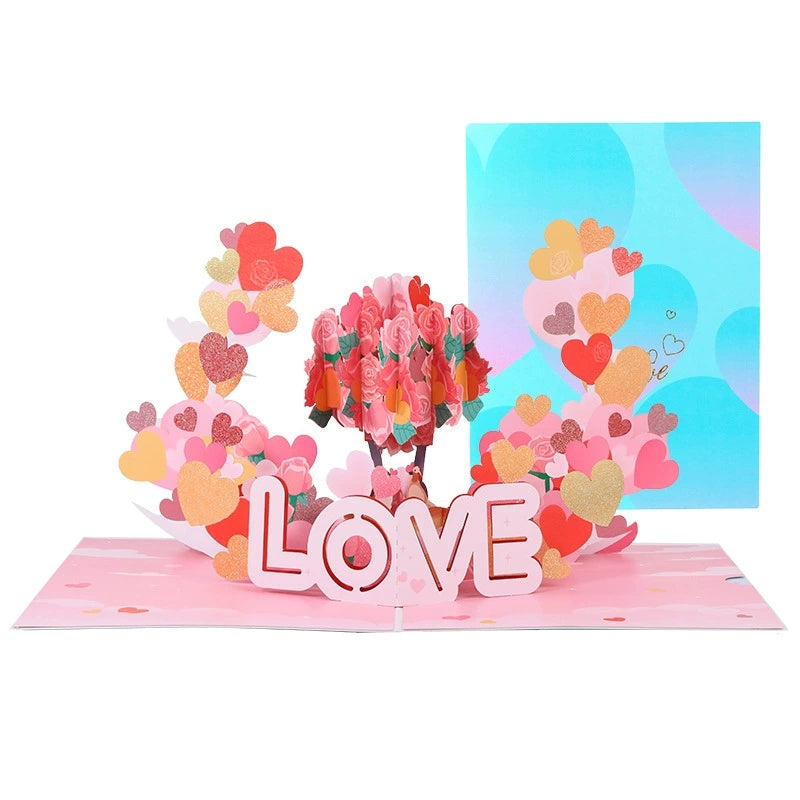 A 3D pop-up greeting card for Valentine's Day with the word 'LOVE' in pink letters surrounded by a floral design and a premium envelope in the background.