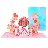 A 3D pop-up greeting card for Valentine's Day with the word 'LOVE' in pink letters surrounded by a floral design and a premium envelope in the background.