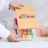 Hand holding a colorful 'Happy Birthday' card with numbers on a soft background
