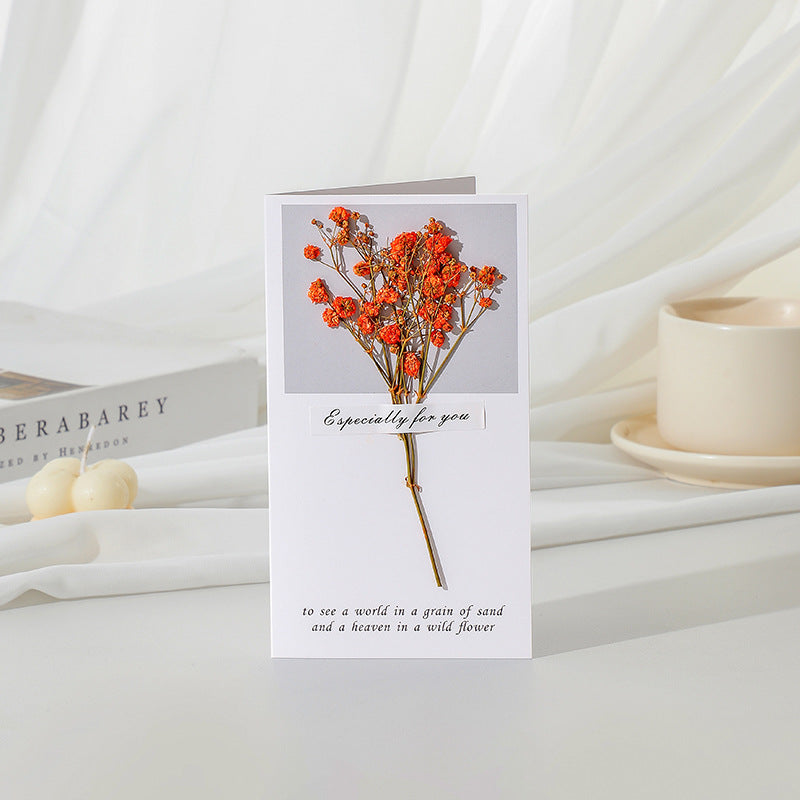 Greeting card with dried flowers on a white surface