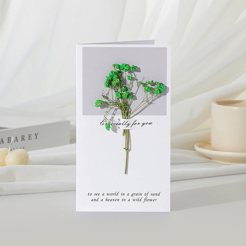 Greeting card with green flowers and text on a white surface