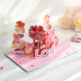 3D pop-up card with flowers and 'LOVE' text on a white surface