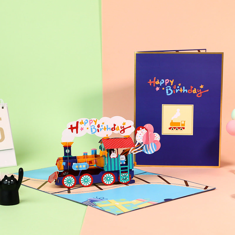Colorful birthday card with a train design on a pink surface