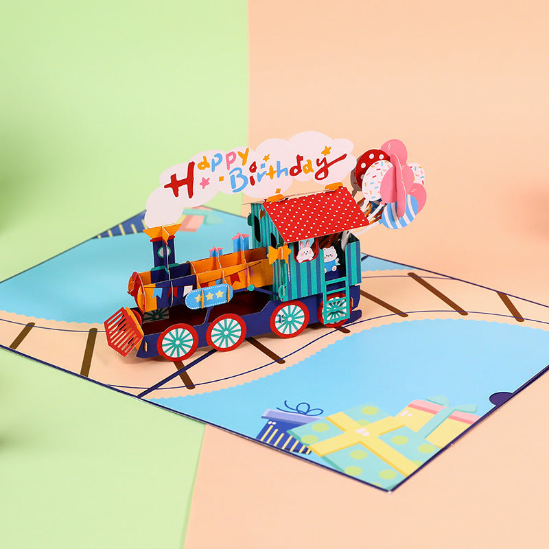 3D paper train with a 'Happy Birthday' sign on a colorful background