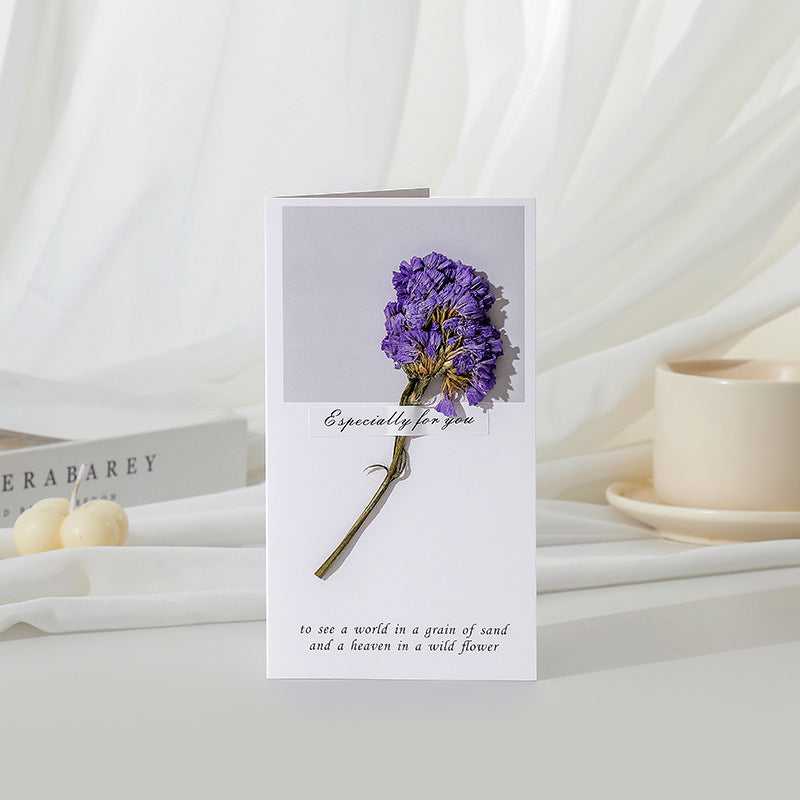 Greeting card with a purple flower and text on a white surface