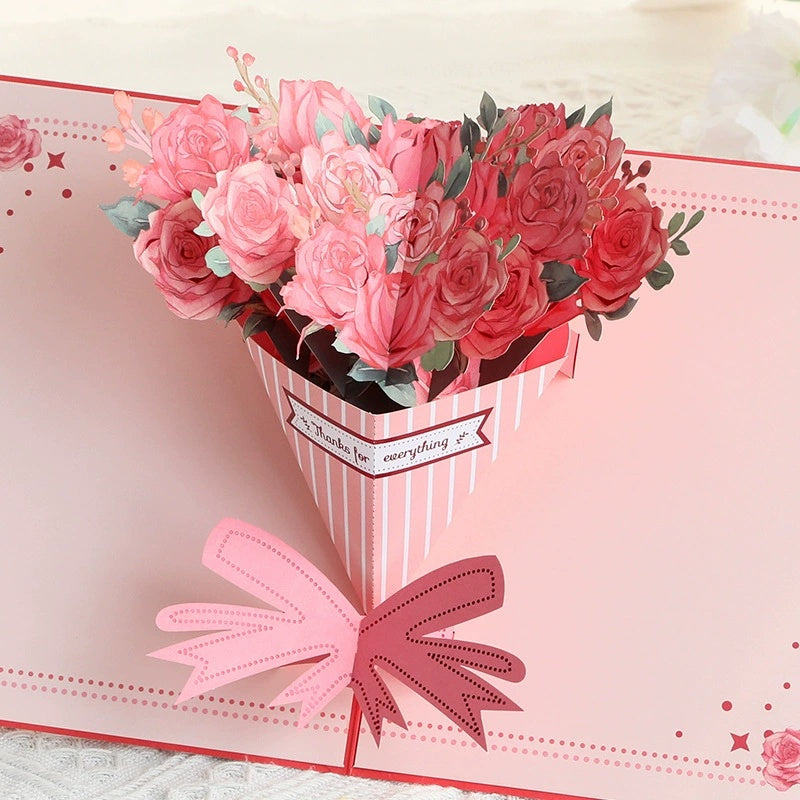 Card with a 3D bouquet of pink and red roses and a pink bow on a light pink background.