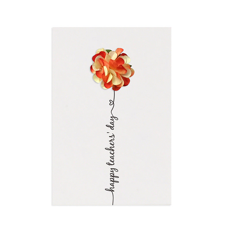 Three handmade greeting cards with preserved flower arrangements, each in different colors, attached to the cards with a pin, displayed on a wooden surface with plants in the background.