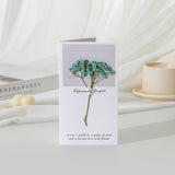 Greeting card with dried flowers and text on a white surface