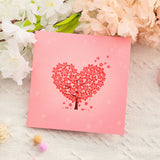 Pink card with a heart-shaped tree design on a floral background
