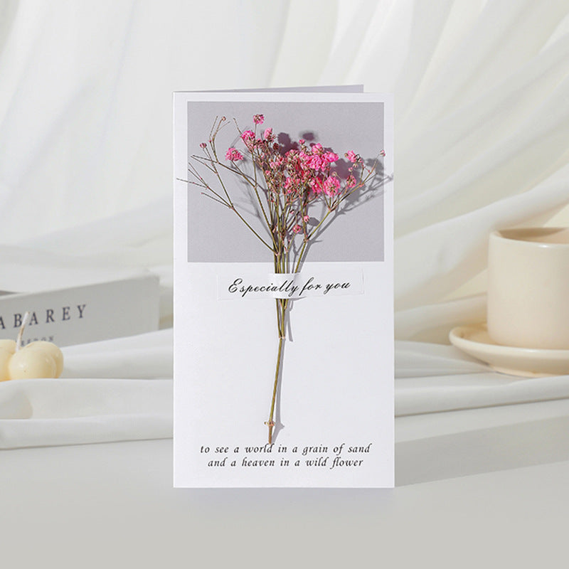 Greeting card with pink flowers and text on a white surface