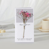 Greeting card with pink flowers and text on a white surface